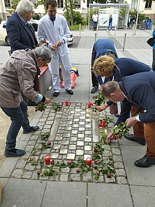 Menschen legen Blumen um Stolpersteine