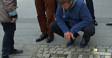 Mann begutachtet eingelassene Stolpersteine
