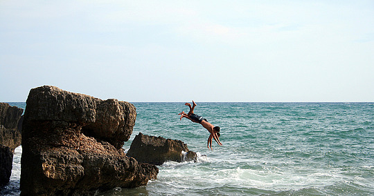 © Michal Adamczyk / stock.adobe.com Zwei junge Männer springen kopfüber vom Felsen ns Meer